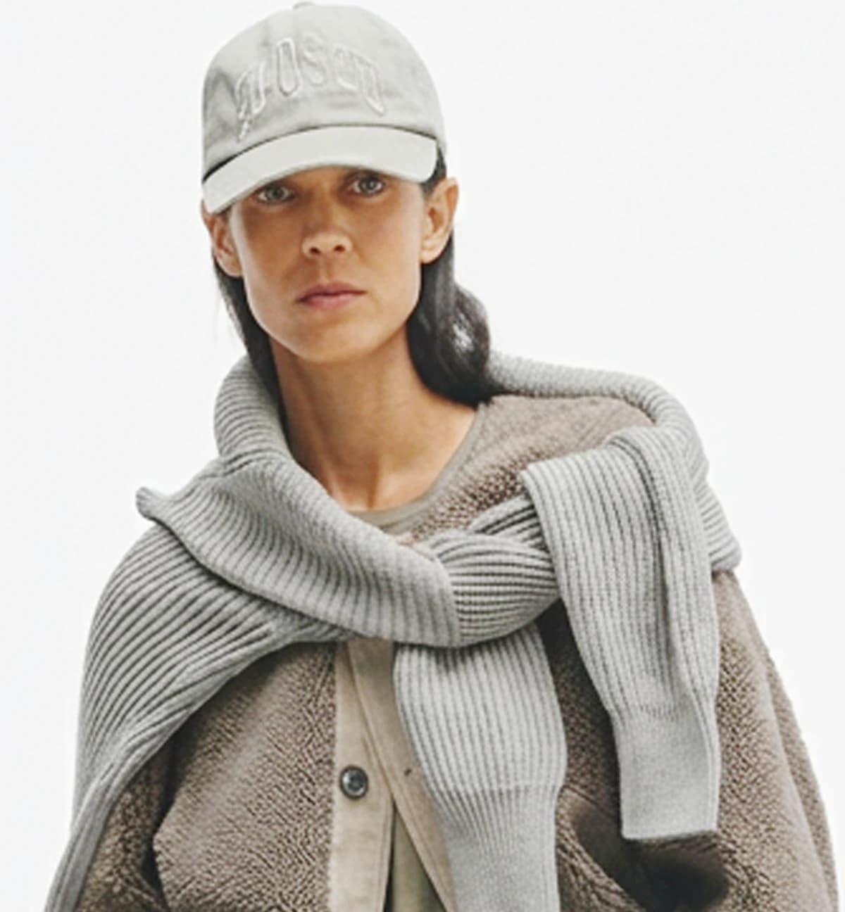 Model wearing layered neutral flat-knit cardigan and ribbed knitwear